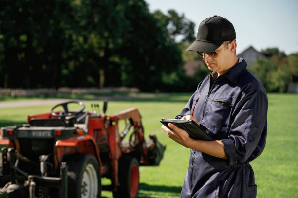 istock Black digital tablet in hands. Man is with utility tractor with grass cutter and aerator equipment on the field 2170941411