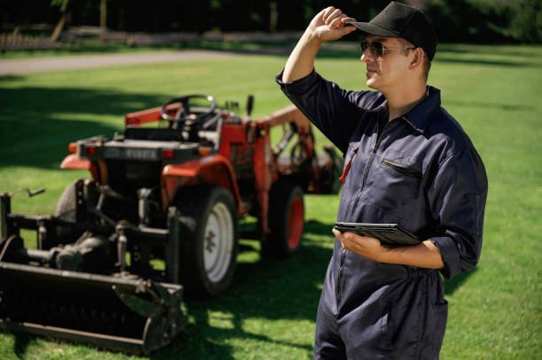 istock Black digital tablet in hands. Man is with utility tractor with grass cutter and aerator equipment on the field 2170941421