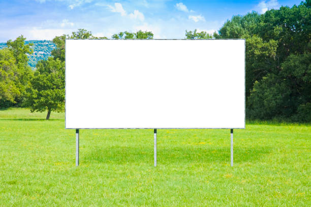 istock Blank advertising metal billboard in a green field with trees on background - image with copy space 2170944933