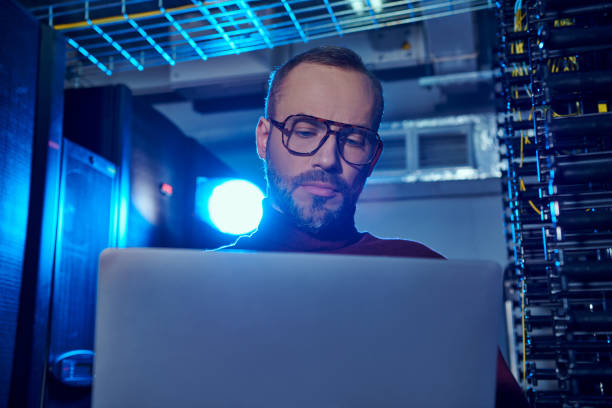 istock Focused technician working on laptop in a modern data center with glowing servers 2170945224