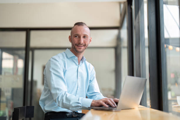 istock Young Determined Businessman Working on Laptop in Modern Office Setting with Natural Light 2170946617
