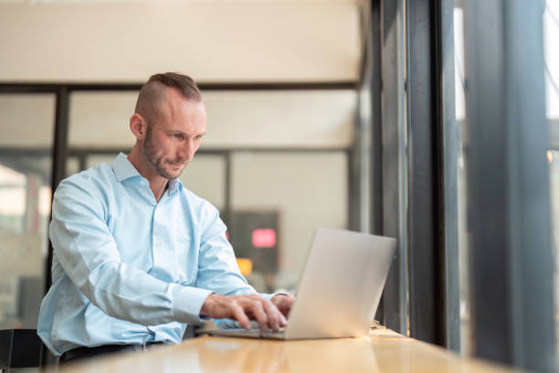 istock Focused Young Businessman Working on Laptop in Modern Office Setting with Determined Expression 2170946636