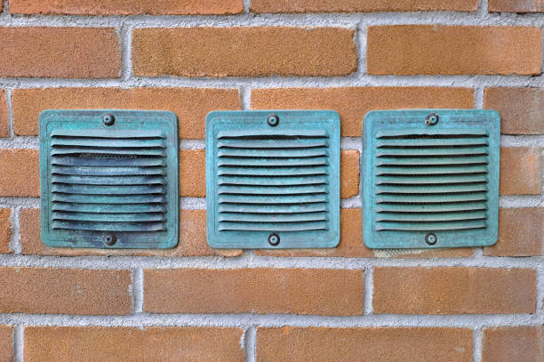 Copper ventilation grilles against a brick wall