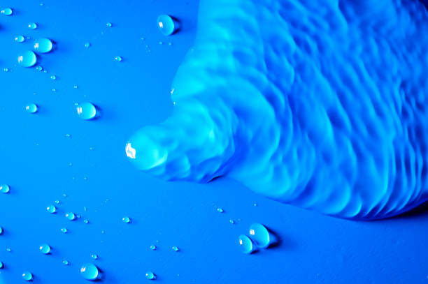 This image is a close up of a blue liquid, with various shades of teal and white. The surface of the liquid appears to be in motion, creating an abstract texture that looks like waves or ripples. In the center of the image there is a splash which creates an interesting contrast against the surrounding area. On either side of this splash are two smaller splashes which add further depth and complexity to the composition. At the bottom right corner there is another small object which could be interpreted as part of a larger pattern or design within this abstract painting-like scene. Overall, this image has an ethereal quality that evokes feelings of tranquility and peace while also providing visual interest through its intricate details and textures.