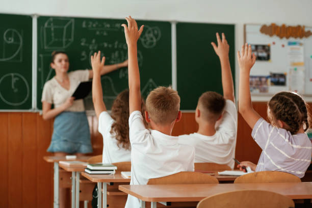 istock With hands up. Pupils, kids in the classroom together 2170968264