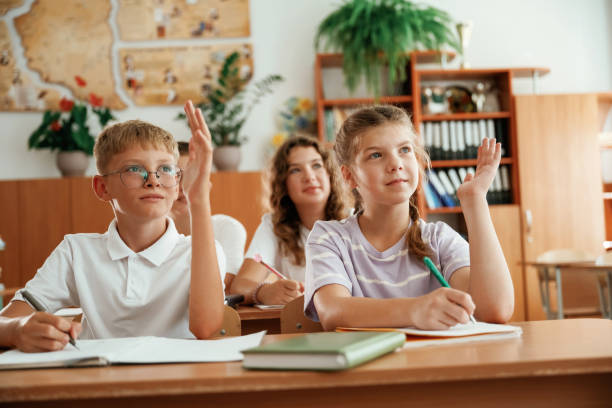 istock With hands up. Pupils, kids in the classroom together 2170968740