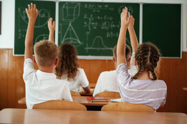 istock With hands up. Pupils, kids in the classroom together 2170969334