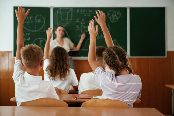 istock With hands up. Pupils, kids in the classroom together 2170969349