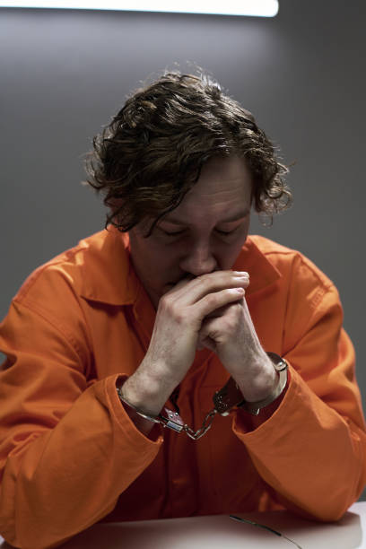 istock Pensive Handcuffed Man Sitting Alone in Orange Jumpsuit 2170970667