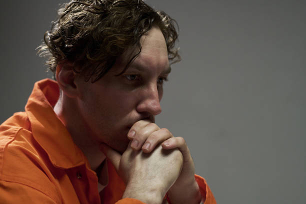 istock Reflecting Man in Orange Jumpsuit with Hands on Chin 2170970703