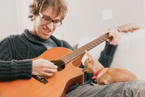 istock Man playing acoustic guitar with curious dog watching him 2170970911