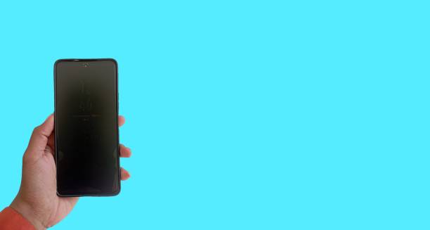 istock Holding a mobile phone on an isolated blue background 2170972563