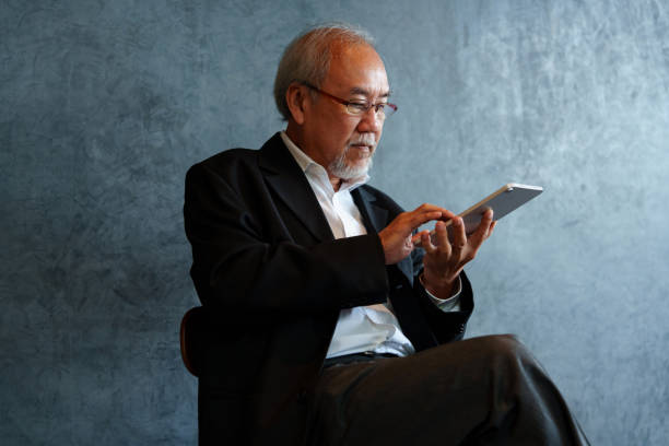 Senior businessman with tablet computer outside of modern office building.