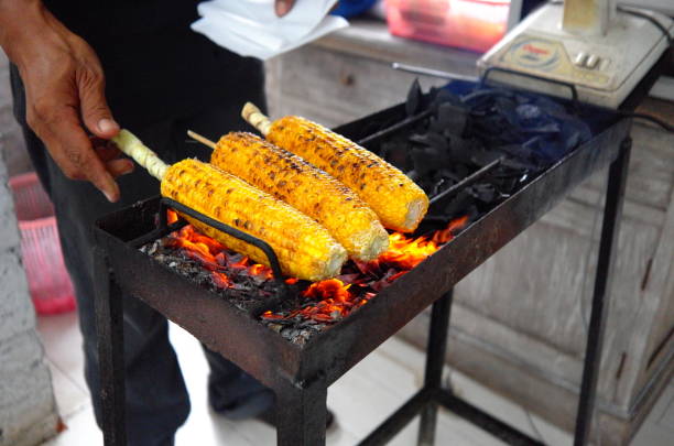 a roasted corn seller is burning corn on a stove