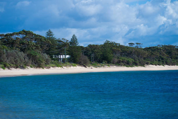 Photo of Timor Leste traditional hut by the beach, calm blue beach background with white sand