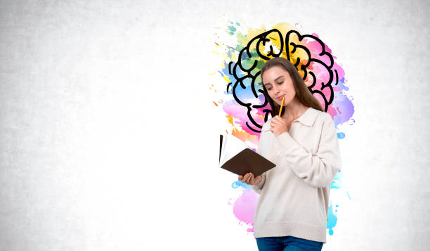 istock Woman student take note in notebook, colorful brain on concrete wall. Copy space 2170997567