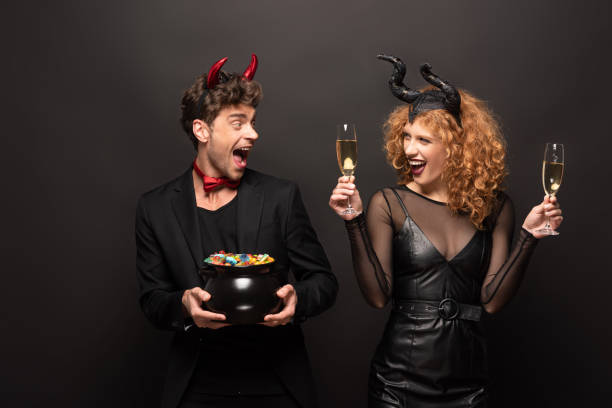 istock Young couple in creative Halloween costumes holding drinks and candy with joyful expressions 2170998943