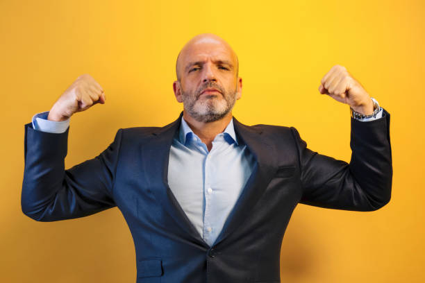 A man in a dark blue suit raises his arms showing strength.