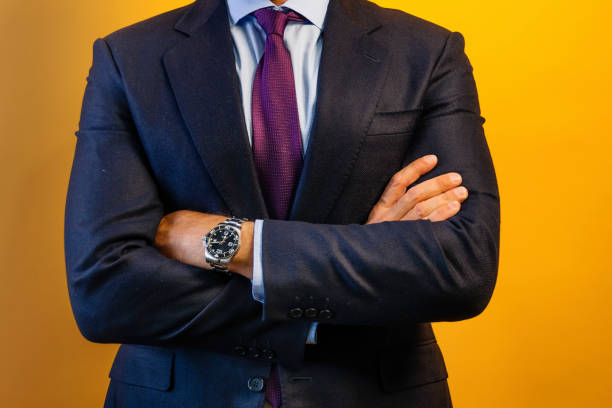 istock An unrecognizable man in a dark blue suit is standing in front of a yellow wall. 2171008640