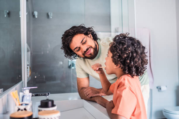 istock Father observing son brushing teeth on his own in the bathroom 2171008649