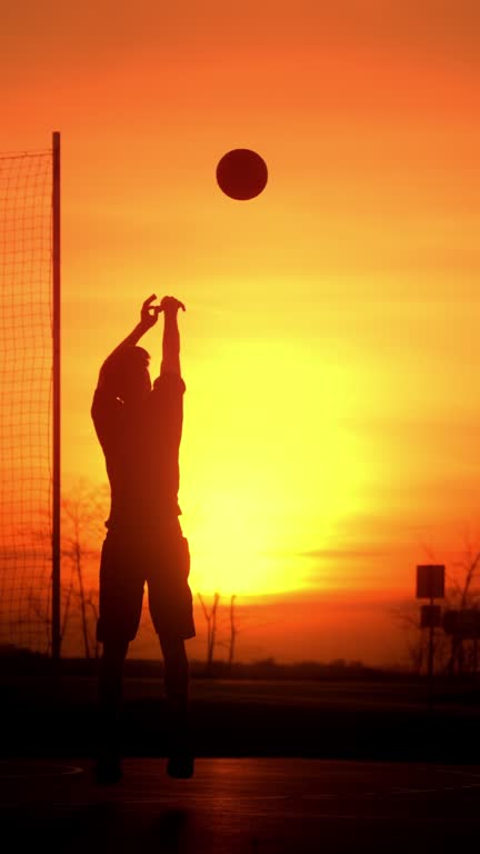 SLO MO Silhouette Young Man Practicing Jump Shot while Playing Basketball with Friend on Open Court at Sunset