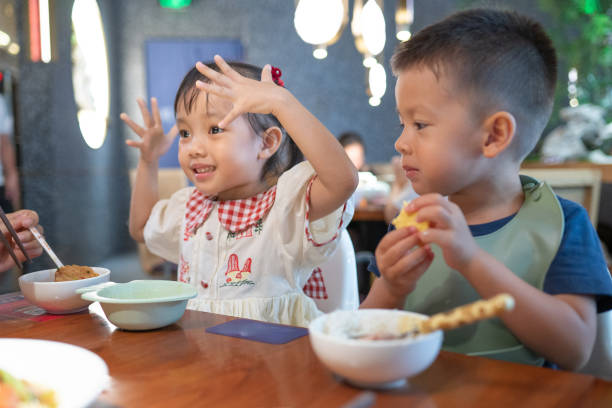 istock Excited little girl chatting with boy at restaurant table 2171013389