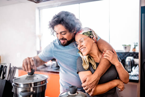 Mature woman battling cancer cooking with her husband and embracing at home