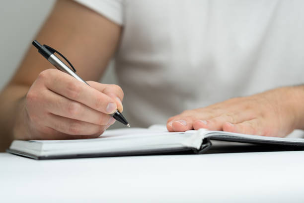 istock Young man hand writing in notebook close up 2171016509