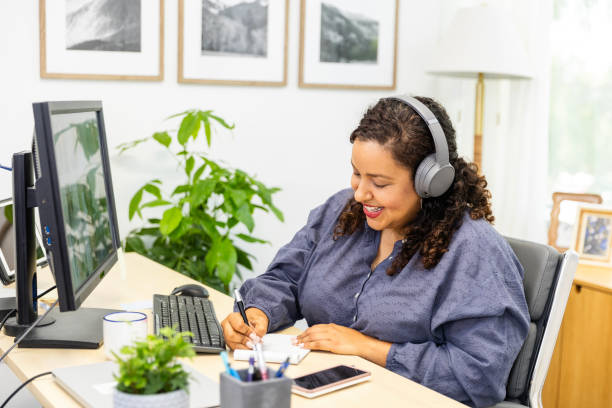 istock Mid adult female takes notes while attending the video conference 2171016692