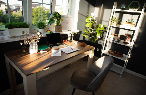 istock Modern, sunlit office desk is neatly arranged with laptop, documents, and coffee cup, surrounded by plants and personal items. Bright atmosphere and organized space reflect productivity and focus 2171018529
