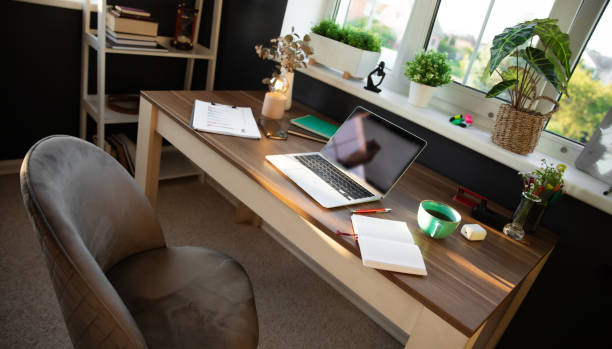 istock Modern, sunlit office desk is neatly arranged with laptop, documents, and coffee cup, surrounded by plants and personal items. Bright atmosphere and organized space reflect productivity and focus 2171019182