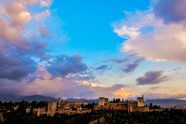 A beautiful blue sky with a few clouds and a mountain in the background. The sky is clear and the sun is setting