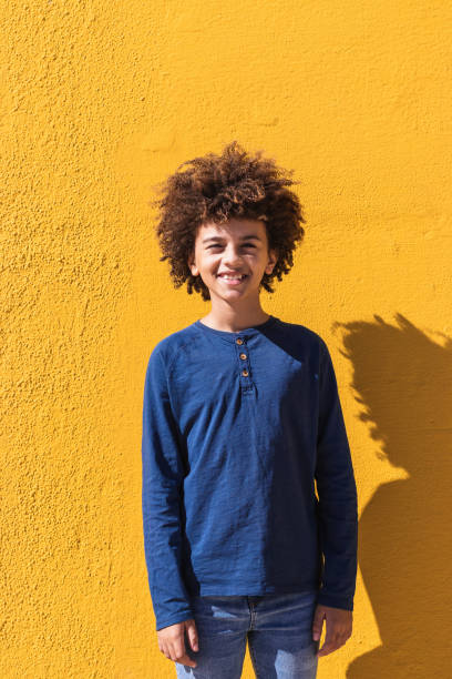 istock Ethnic boy with curly hair standing on yellow wall 2171020567