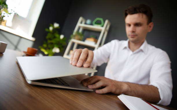 istock A man in a white shirt opens his laptop in a modern office setting, with a bookshelf visible in the background. The photo captures a moment of preparation and focus in a professional environment. 2171020935