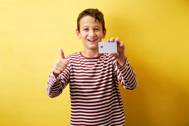 istock Cheerful Young Boy Showing Card on Yellow Background 2171026921