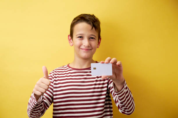 istock Cheerful Young Boy Showing Card on Yellow Background 2171026922