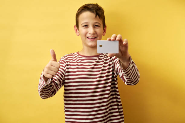 istock Cheerful Young Boy Showing Card on Yellow Background 2171026931