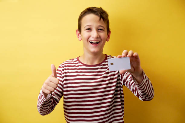 istock Cheerful Young Boy Showing Card on Yellow Background 2171026938