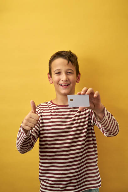 istock Cheerful Young Boy Showing Card on Yellow Background 2171026942