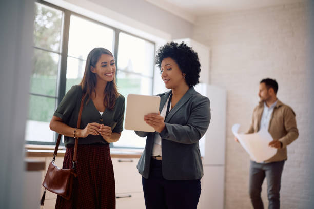 istock Happy woman using digital tablet with real estate agent while looking for a new home. 2171027403