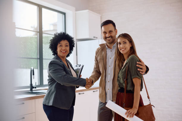 istock Happy couple and real estate agent shaking hands and looking at camera. 2171027455