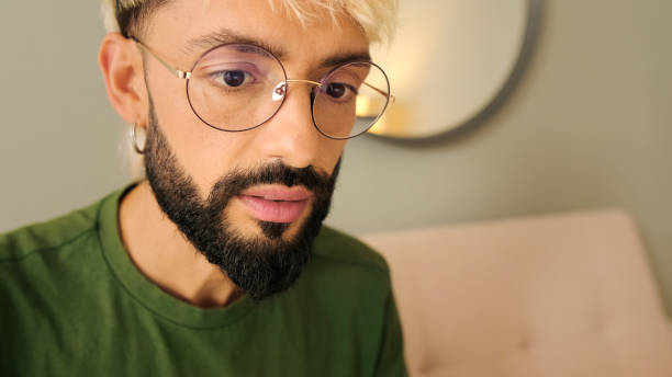 istock Close-up of a young blond man with a beard wearing glasses reading, looking through information 2171031103