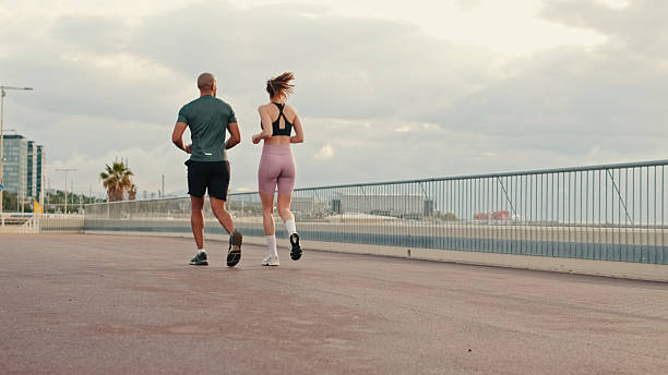 istock Back view of young active couple jogging together along beautiful seafront 2171031586