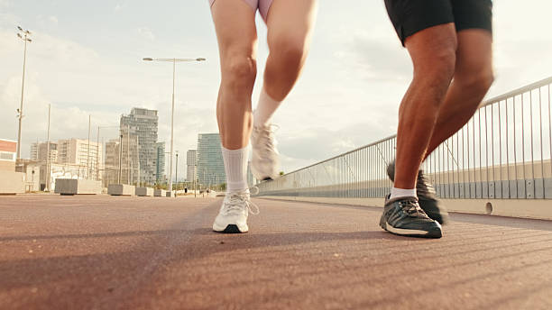 istock Young joyful active couple jogging together along beautiful seafront, sneaker-foot focus, ground focus 2171031933