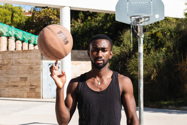 Determined African American male basketball player spinning and balancing ball on finger while looking at camera