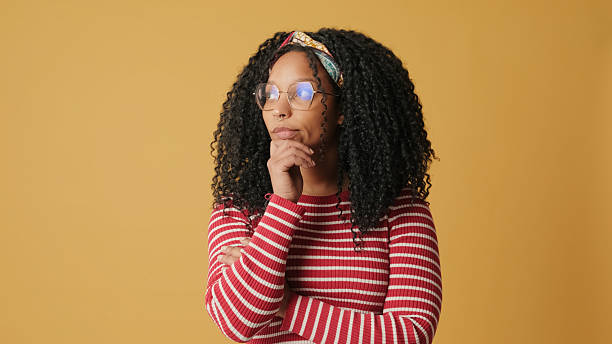 istock Confused woman cannot make choice on yellow background in the studio 2171034798
