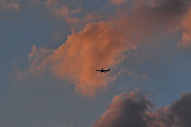 jetliner flying under an azure blue sky, covered by clouds shaded by the twilight sun - POA,  SAO PAULO,  BRAZIL.