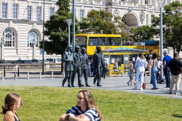 Liverpool, England - July 29, 2024: This image shows visitors at the Port of Liverpool viewing the Beatles Statue on the plaza.