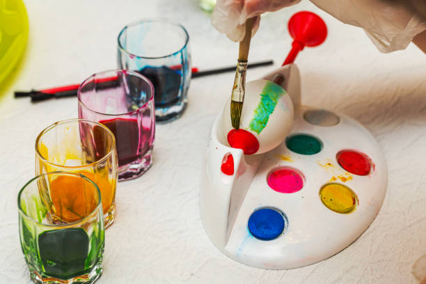 istock Close-up view of Easter egg painting process with colorful paints and brushes on white table. Sweden. 2171040720