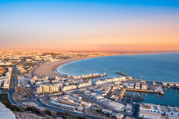 Agadir, Morocco at sunset. Panoramic view of Agadir city and bay in southern Morocco with Marina, beach and ocean from Oufla or Casbah fortress. Moroccan seaside resort on Atlantic coast in Africa Agadir, Morocco at sunset. Panoramic view of Agadir city and bay in southern Morocco with Marina, beach and ocean from Oufla or Casbah fortress. Moroccan seaside resort on Atlantic coast in Africa. sunset agadir marocco stock pictures, royalty-free photos & images